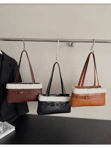 Three plush leather handbags in brown, black, and caramel hanging on a metal rack