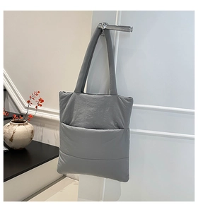 Detail of grey quilted puffer tote bag hanging on a white door in a modern home setting