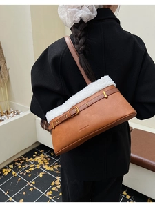 Close-up of caramel leather shoulder bag with white faux fur trim and gold buckle detail