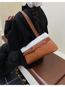 Detail view of brown leather shoulder bag with white plush trim and buckle strap decoration