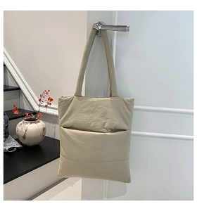 Close-up of beige quilted puffer tote bag hanging on a door handle for daily commute