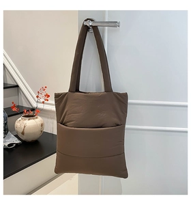 Deep brown quilted puffer tote bag hanging on a door handle in a modern home interior