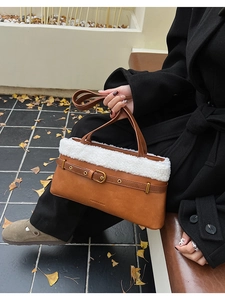 Detail of brown leather handbag featuring plush white faux fur trim and gold buckle