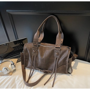 Vue détaillée du sac cabas marron vintage avec rivets métalliques et franges