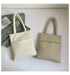 Detailed view of quilted puffer tote bags in cream and khaki with padded straps