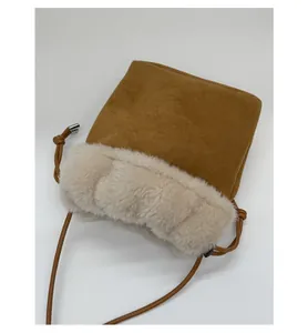 Dettaglio del bordo in peluche beige e pelle scamosciata marrone sulla borsa a secchiello