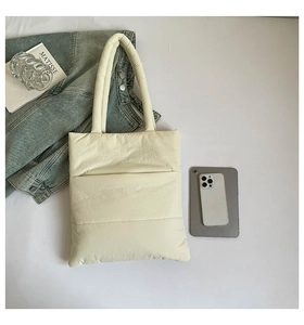 Detail of cream quilted down tote bag featuring soft padded handles and puffer texture