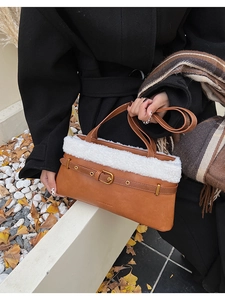 Detail of caramel PU bag with white faux fur trim and gold belt buckle on autumn leaves