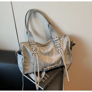 Macro detail of soft grey tote bag featuring rivet accents and decorative cross straps