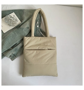 Quilted down fabric tote bag detail in light beige with soft padded handle and modern square stitching