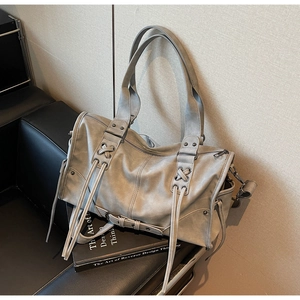 Détail des rivets vintage et des lacets sur le sac Boston en daim gris texturé