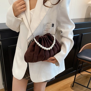 Sac seau marron plissé avec anse en perles et chaîne argentée sur blazer blanc