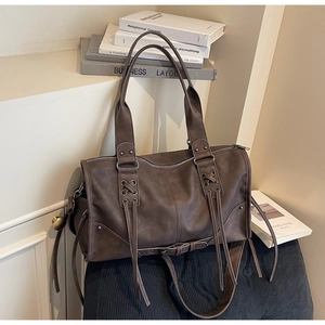 Detail of dark brown leather tote bag with unique tassel design and vintage texture