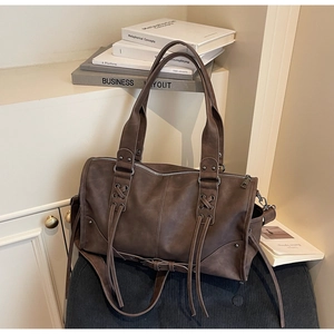 Détails des poignées à lacets et ferrures argentées sur un sac à main vintage marron
