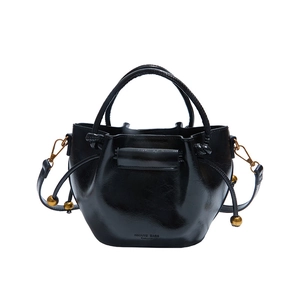 Minimalist black glossy leather bucket bag with gold hardware and drawstring closure