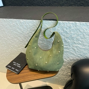 Dettaglio della borsa hobo in pelle scamosciata verde con rivetti dorati su legno
