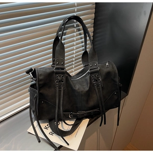 Détail latéral d'un sac Boston noir vintage avec œillets métalliques et bandoulière chic