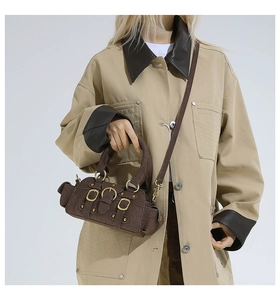 Detail of dark brown suede handbag with golden metal buckles and studs in retro style
