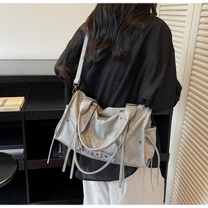 Détail du sac cabas gris avec de longues franges et rivets sur cuir souple et mat
