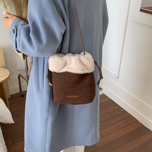 Dettaglio del bordo in peluche e logo sulla borsa a secchiello in pelle scamosciata