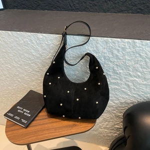 Dettaglio della borsa hobo in camoscio nero con borchie dorate e tracolla regolabile