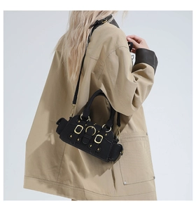 Detail of black utility bag with golden metal buckles and adjustable strap on a model