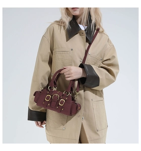 Detail of a dark red retro handbag featuring golden buckles and adjustable shoulder straps