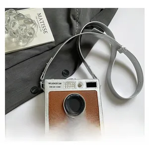 Macro detail of camera-shaped crossbody bag featuring silver metallic and brown leather finish