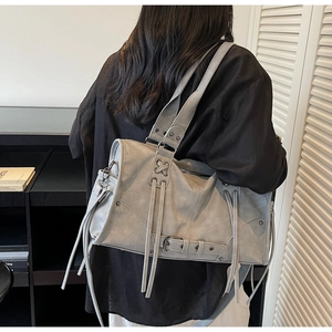 Détail du sac cabas gris à franges avec glands et boucle vu de l'arrière en portage