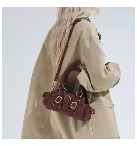 Detail of burgundy matte leather crossbody bag with vintage gold buckles and dual handles
