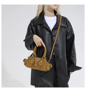 Close-up of brown suede handbag with decorative metal buckles and utility pockets