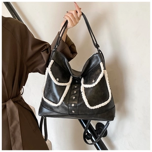Detail of black PU shoulder bag with dual sheepskin-fleece pockets and silver rivet studs