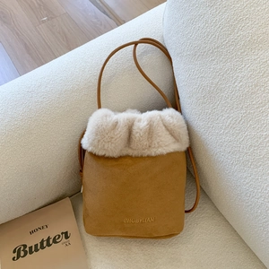 Secchiello in pelle scamosciata marrone con bordo in ecopelliccia beige su divano bianco