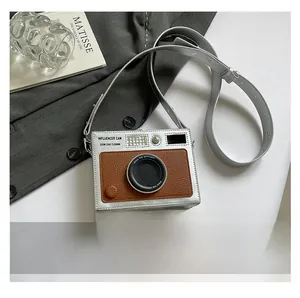 Mini vintage camera crossbody bag shown next to a smartphone for size scale comparison