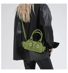 Detail of green leather handbag with decorative buckles, metal studs and top handle