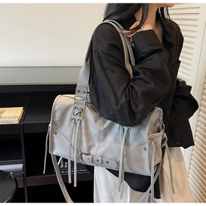 Détail du sac bandoulière en cuir gris avec pompons et rivets métalliques élégants