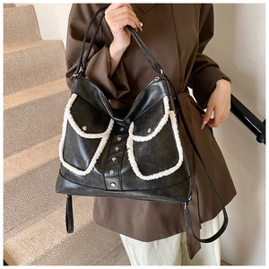 Lifestyle shot of large black leather tote bag with white plush trim and studs detail