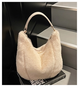 Detail of beige plush hobo bag with faux fur texture and leather handle on a luxury prop