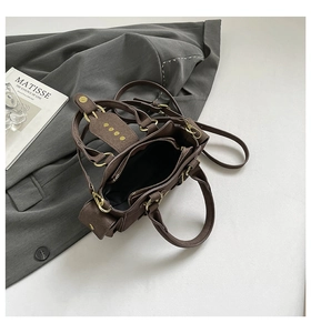 Flat lay of vintage dark brown faux leather handbag with retro gold studs and strap