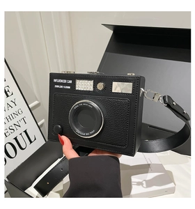 Detail of camera-shaped crossbody bag with influencer lettering and silver hardware