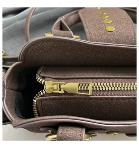 Close-up of golden zipper and rivet detail on brown suede French vintage handbag