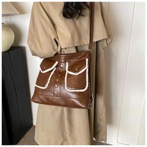 Detail of vintage brown PU leather shoulder bag with white fleece trim and metal studs