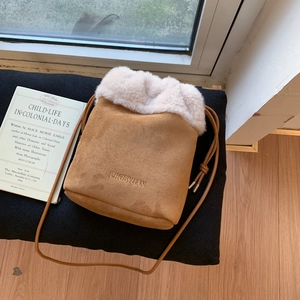 Dettaglio borsa a secchiello in camoscio caramello con bordo in peluche e logo ricamato