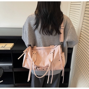 Pink moto tote bag with tassels and studs worn by a model to show large capacity and size
