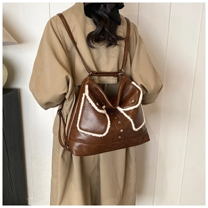 Detail of dark brown leather backpack with white faux fur trim and metal studs worn with coat