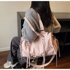 Détail d'un sac cabas rose clair avec laçage croisé et tirettes de fermeture à franges