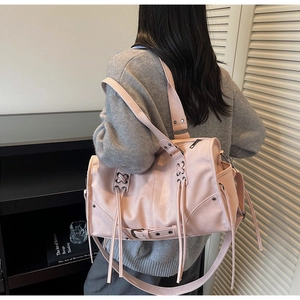 Sac à bandoulière rose avec lacets croisés, pompons et détails d'oeillets métalliques
