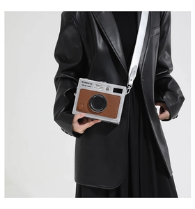 Detail view of vintage camera-shaped crossbody bag with wide silver strap and leather trim