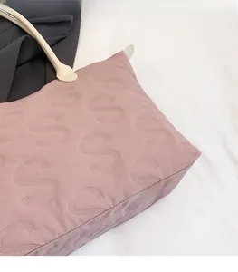 Detail of pink quilted tote bag with stitched S-pattern and cream shoulder strap