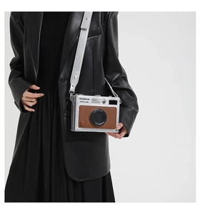 Detail of trendy retro camera cross-body bag featuring silver metallic finish and wide strap
